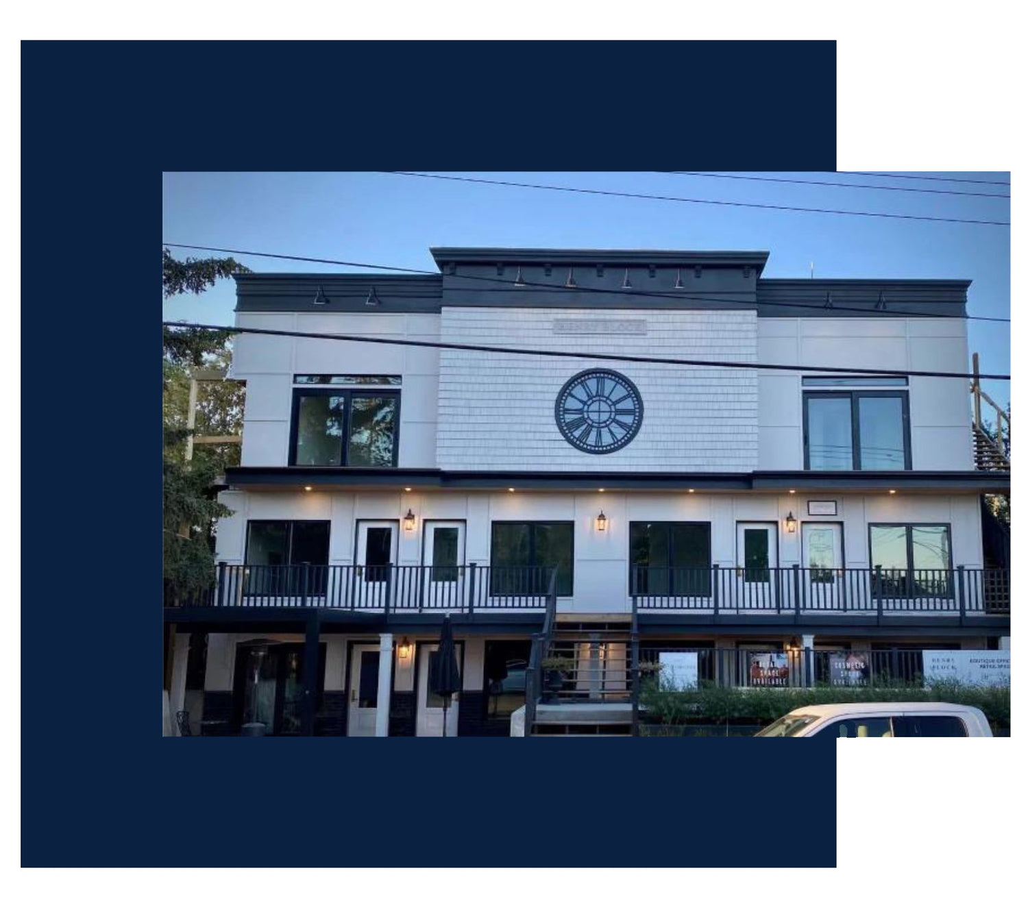 Exterior view of Revive Attire's storefront in Calgary, featuring a modern two-story building with large windows, a central decorative clock design, and inviting entrance with warm lighting.